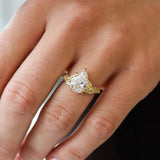 hand wearing large pear diamond engagement ring with leaves 