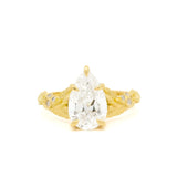 gold engagement ring with pear diamond and leaves on a white background