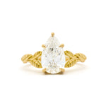 gold engagement ring with leaf detail on band and large pear diamond on a white background