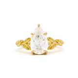 gold engagement ring with leaf detail on band and large pear diamond on a white background