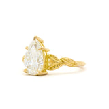 Gold ring with a pear-shaped diamond on a white background