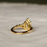 back view of pear engagement ring with leaf detail on a beige fabric