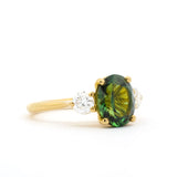 Gold ring with a green gemstone on a white background side view
