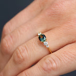 Close-up of a hand wearing a ring with a green gemstone on a blurred background
