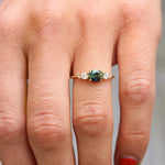 Gold ring with a green gemstone on a person's finger