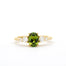gold engagement ring with a green oval sapphire and four diamonds in tapered composition on a white background