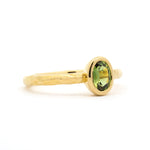Gold ring with a green gemstone on a white background