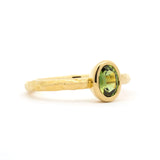 Gold ring with a green gemstone on a white background