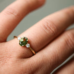Gold ring with a green gemstone on a person's finger