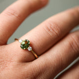 Gold ring with a green gemstone on a person's finger