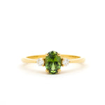 Gold ring with a green gemstone and smaller diamonds on a white background