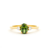 Gold ring with a green gemstone and smaller diamonds on a white background