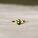 Gold ring with a green gemstone on a textured surface