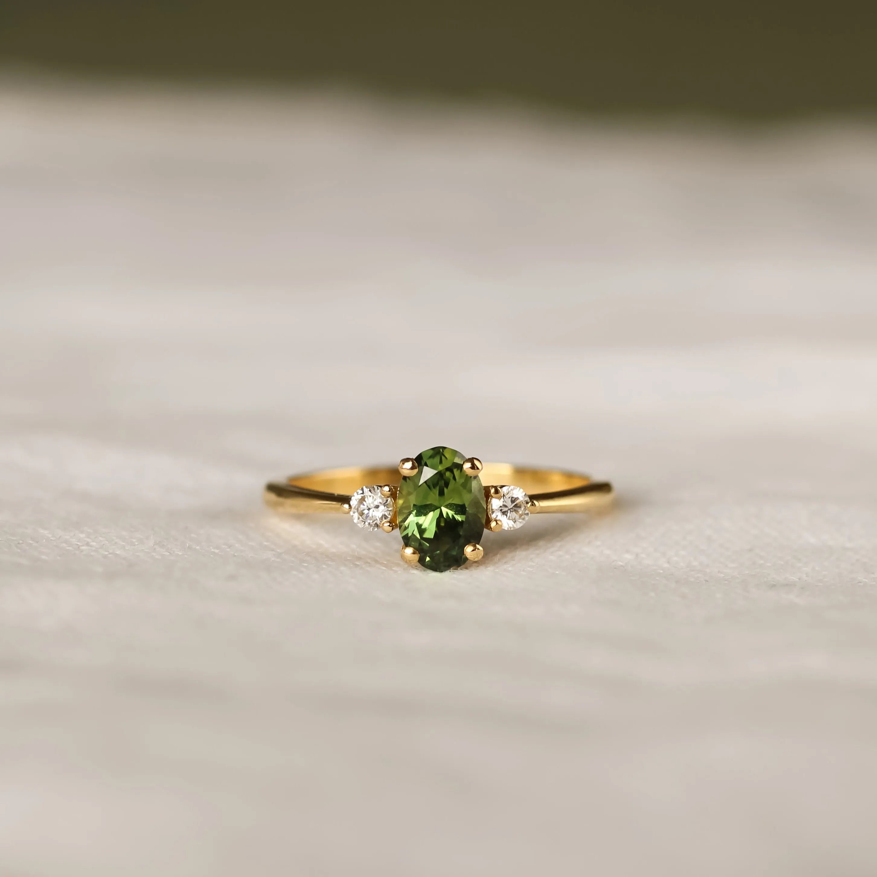 Gold ring with a green gemstone on a textured surface
