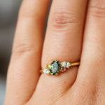 close up of finger wearing green sapphire colourful engagement ring