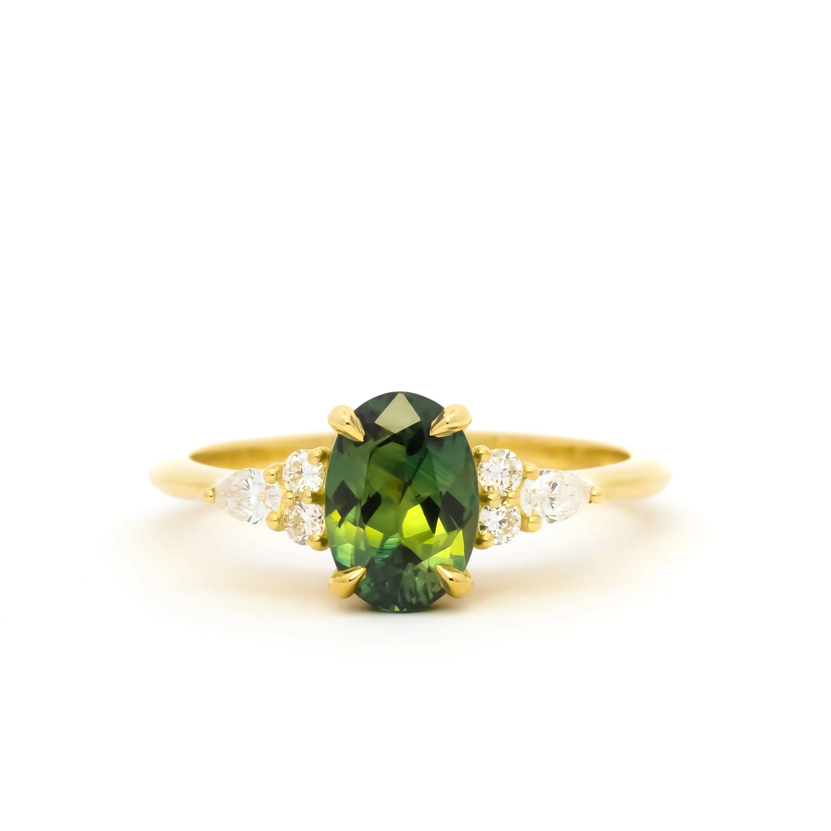 Gold ring with a green gemstone and small round and pear-shaped diamonds on a white background