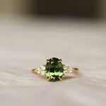 Ring with a large green gemstone and gold setting on a neutral background