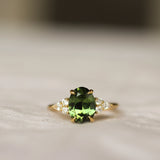 Ring with a large green gemstone and gold setting on a neutral background