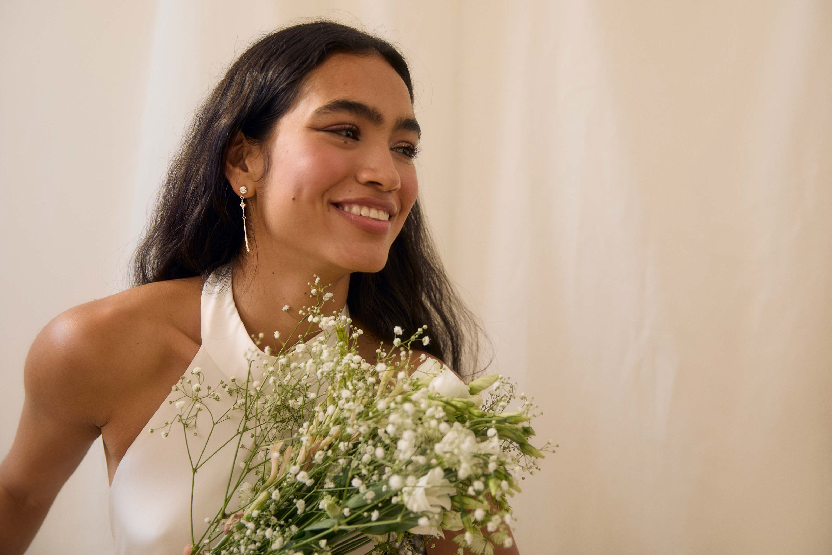 brunette bride wearing white gold dangle diamond earrings with flowers