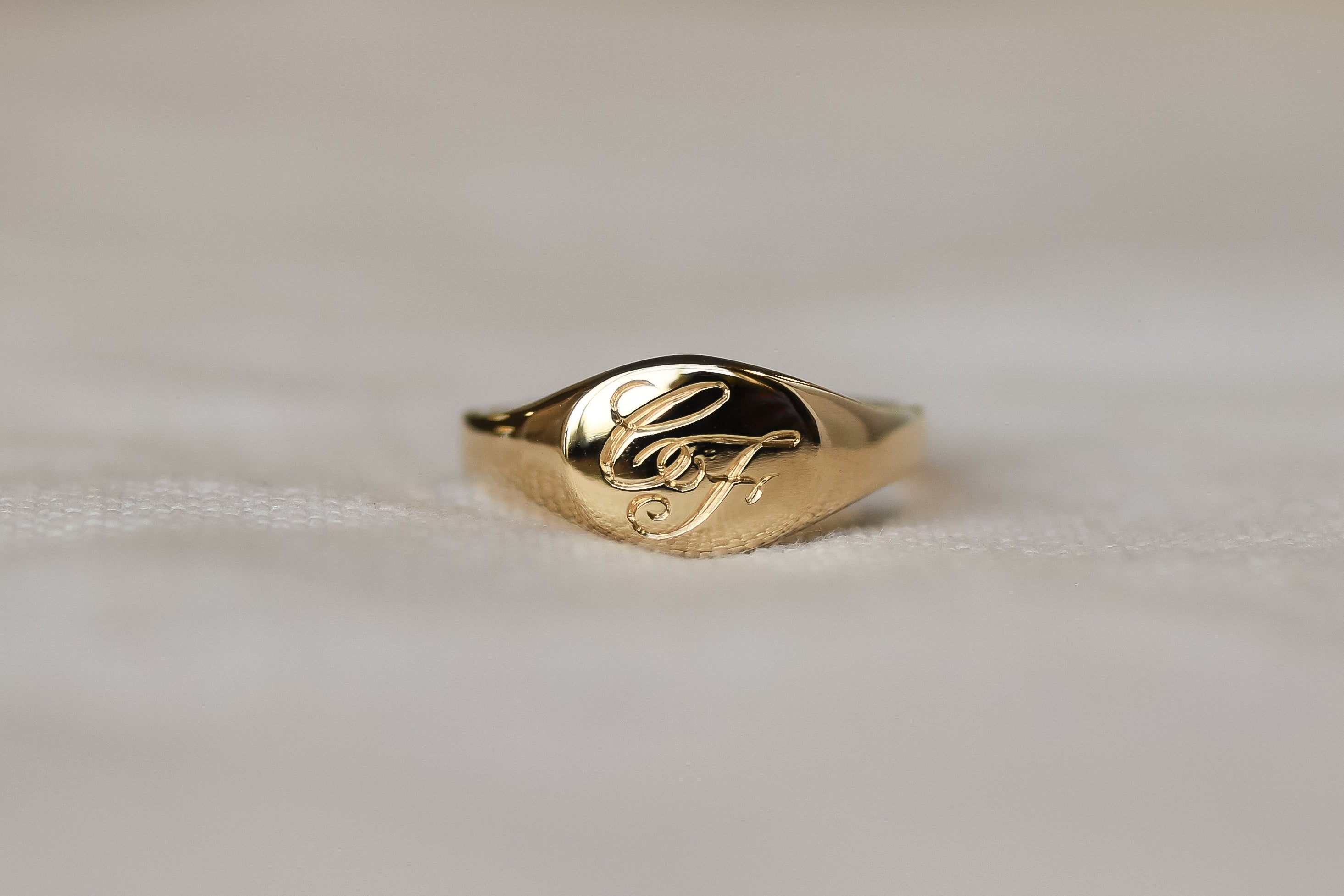 Gold ring with engraved design on a light background