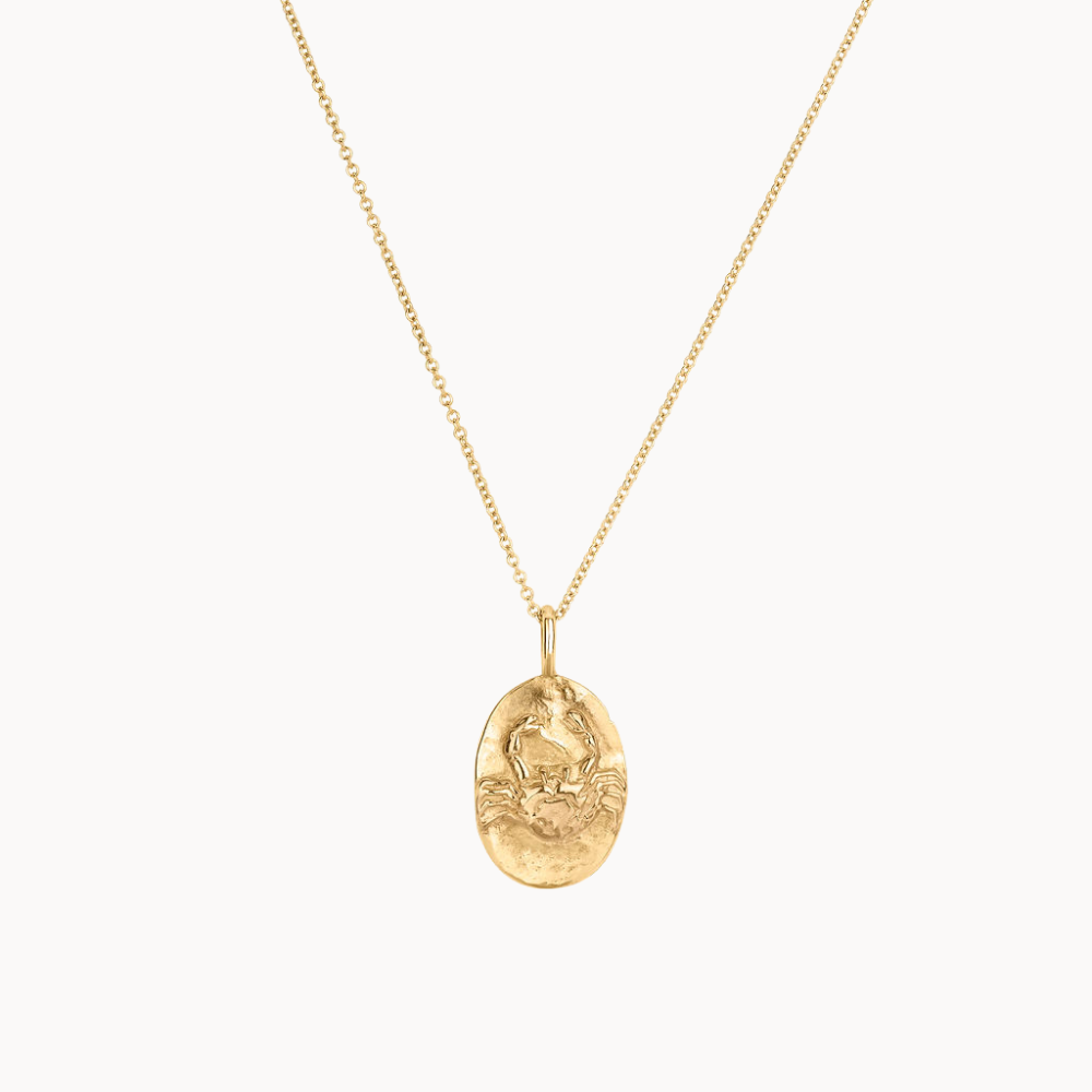 Gold cancer crab necklace with an oval pendant on a white background