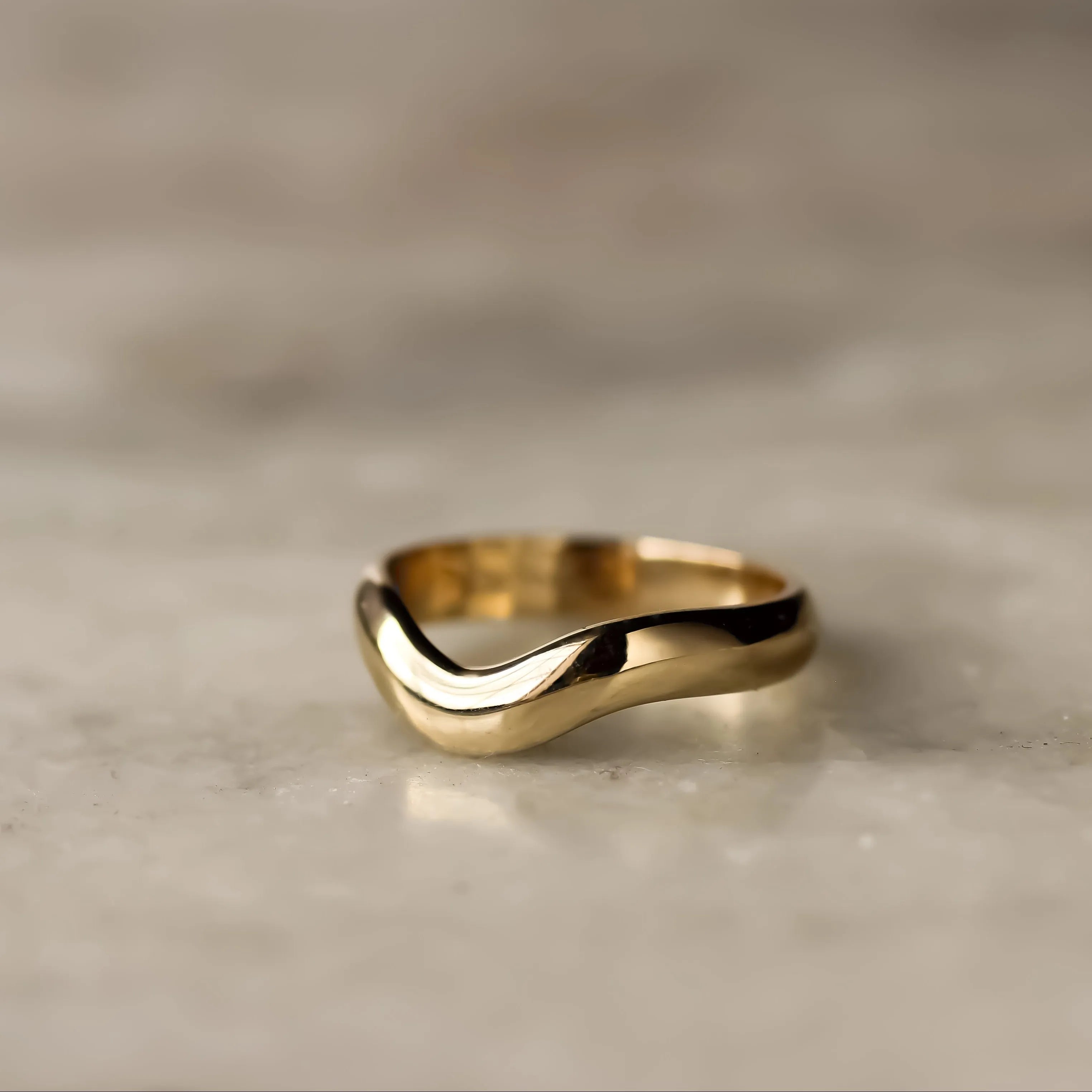 Gold ring with a wavy design on a marble surface