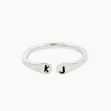 silver open ring with 'k' and 'j' stamped initials on a white background