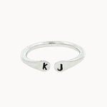 silver open ring with 'k' and 'j' stamped initials on a white background