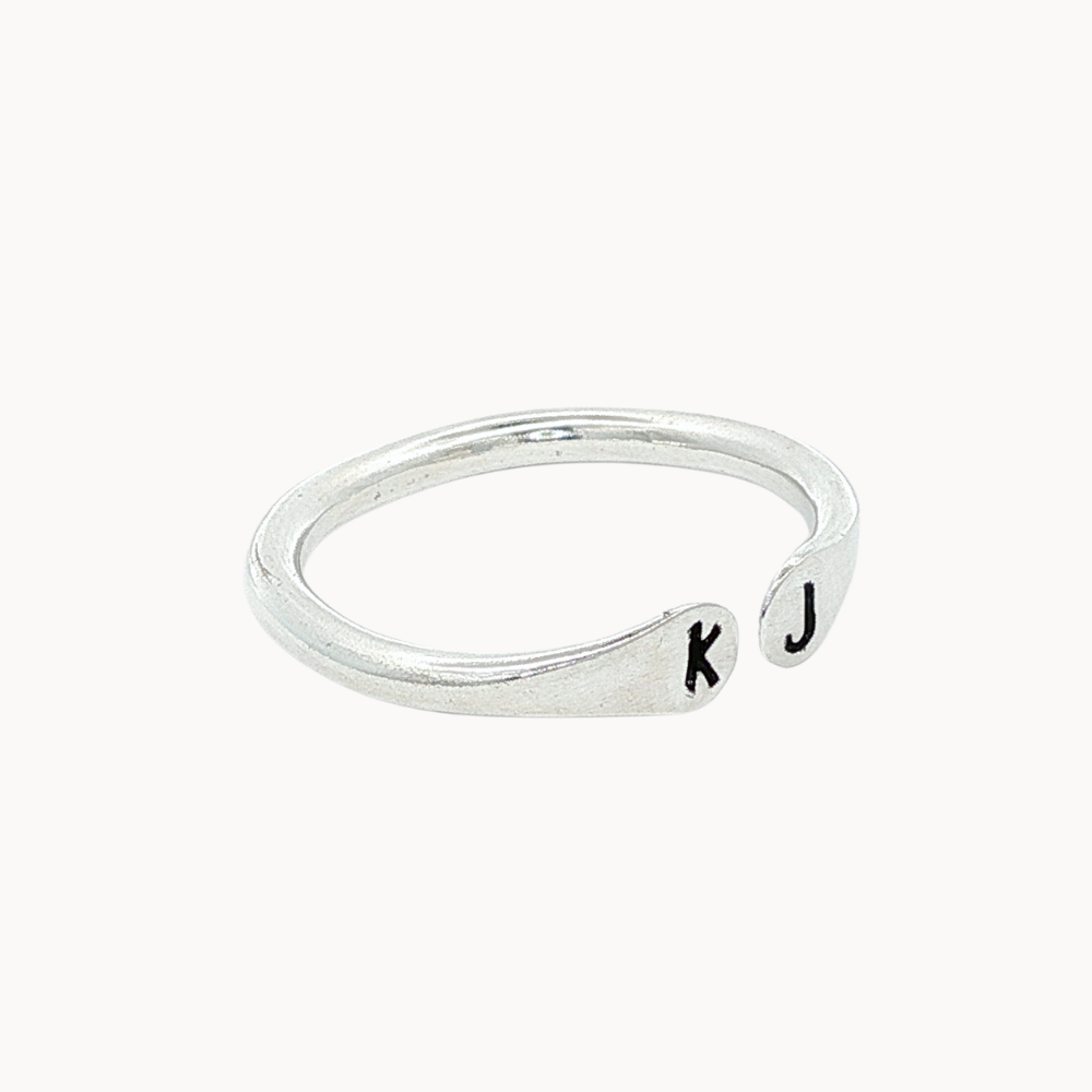 Side view of a silver ring with open top with 'k' and 'j' stamped