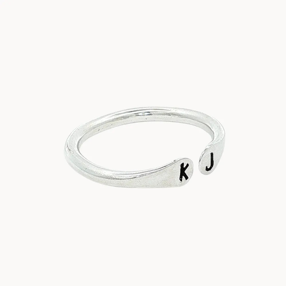 Side view of a silver ring with open top with 'k' and 'j' stamped