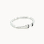 Side view of a silver ring with open top with 'k' and 'j' stamped