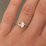 Close-up of a hand wearing a diamond ring with blue gemstones on a neutral background