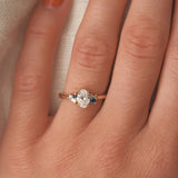 Close-up of a hand wearing an elegant ring with a diamond and blue gemstone on a neutral background.