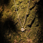 fingerprint pendant necklace infront of moss