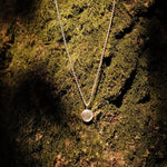 fingerprint pendant necklace infront of moss