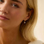 Close-up of a blonde woman wearing a gold hook diamond earring with blurred foreground