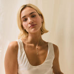Blonde model wearing scoop neck wedding dress, diamond studs and y-shaped drop diamond necklace
