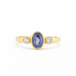 Gold ring with a blue gemstone and two smaller diamonds on a white background