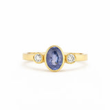 Gold ring with a blue gemstone and two smaller diamonds on a white background