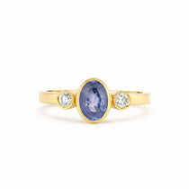 Gold ring with a blue gemstone and two smaller diamonds on a white background