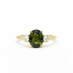 large green sapphire engagement ring with round accent lab grown diamonds on a white background