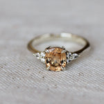 Ring with a peach-colored gemstone on a textured fabric background