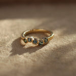 Gold ring with embedded stones on a textured surface