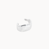 Silver ear cuff with organic texture on a white background