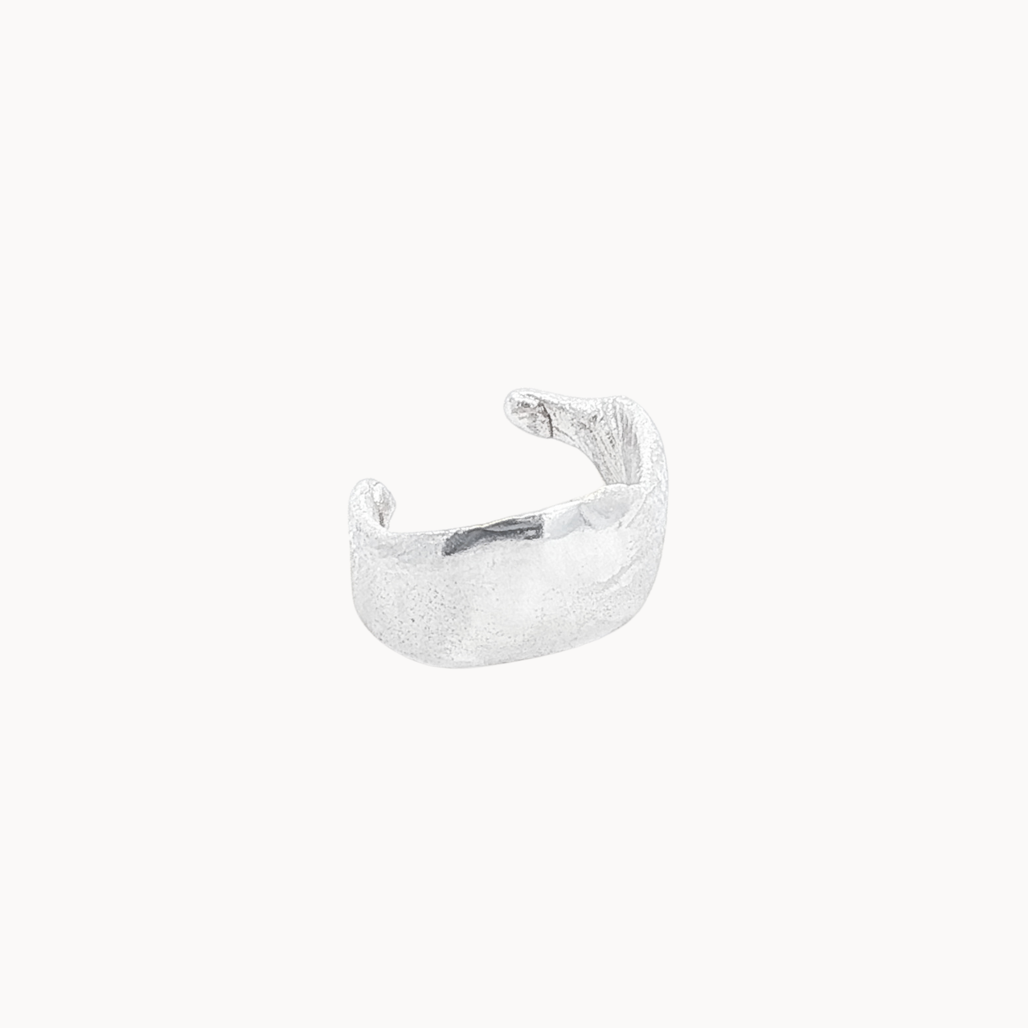 Silver ear cuff with organic texture on a white background