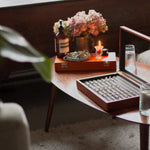 Wooden jewelry box on a table with a candle and flowers in the background