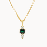 A gold pendant necklace featuring a central rectangular green emerald-cut stone, flanked by clear marquise and round stones, suspended from a delicate gold chain on a light gray background.