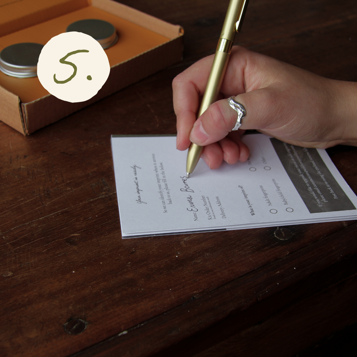 close up of hand wearing a silver ring writing on a form with a gold pen