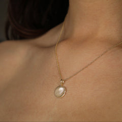 Gold necklace with a fingerprint pendant on a person's neck