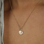 Gold necklace with a small fingerprint pendant on a person's neck
